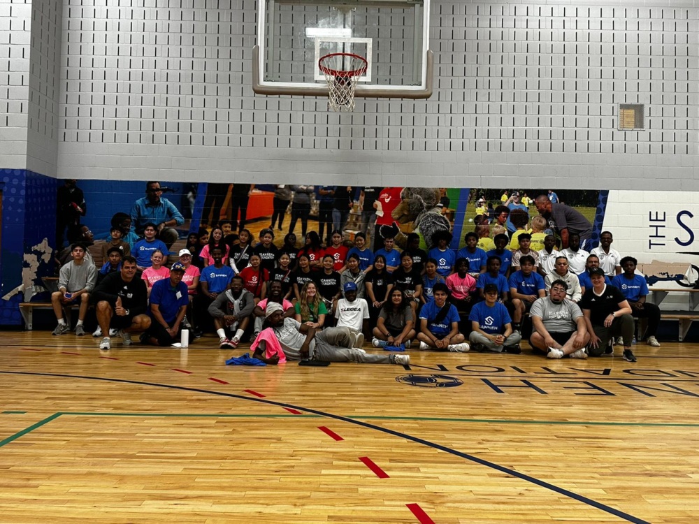 A group of coaches pose for a group photo at a school gym